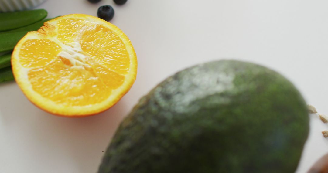 Close-Up of Fresh Avocado and Half Orange on White Surface - Free Images, Stock Photos and Pictures on Pikwizard.com