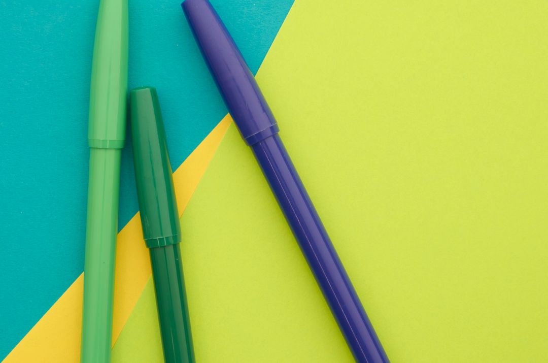 Bright marker pens resting on vibrant geometric paper for creative stationery concept
