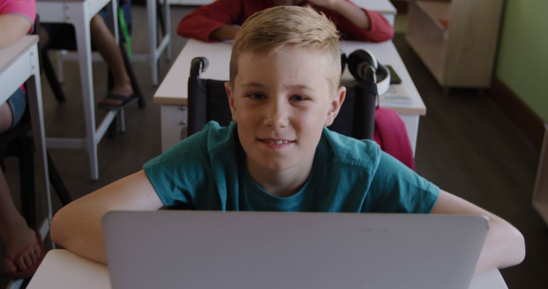 Smiling Boy Sitting at Desk with Laptop in Classroom - Free Images, Stock Photos and Pictures on Pikwizard.com