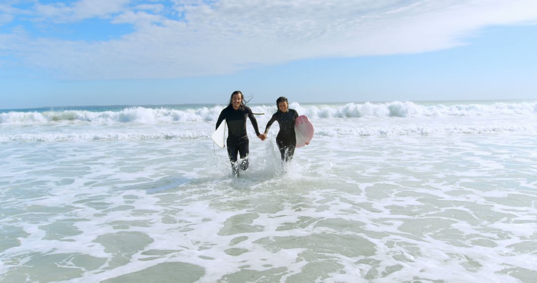 Friends Running into Ocean with Surfboards on Sunny Day - Free Images, Stock Photos and Pictures on Pikwizard.com