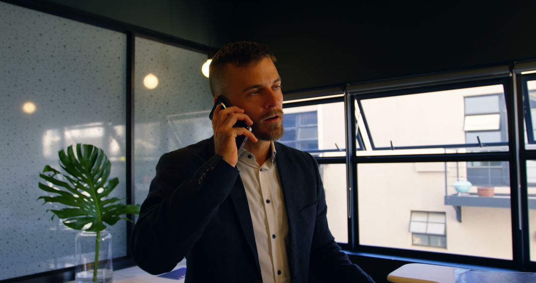 Business Person Talking on Phone by Office Window - Free Images, Stock Photos and Pictures on Pikwizard.com