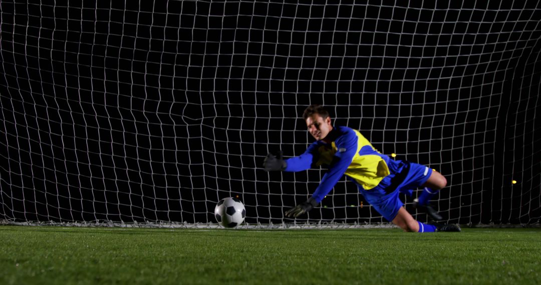 Goalkeeper Making a Dive to Save in Soccer Game at Night - Free Images, Stock Photos and Pictures on Pikwizard.com