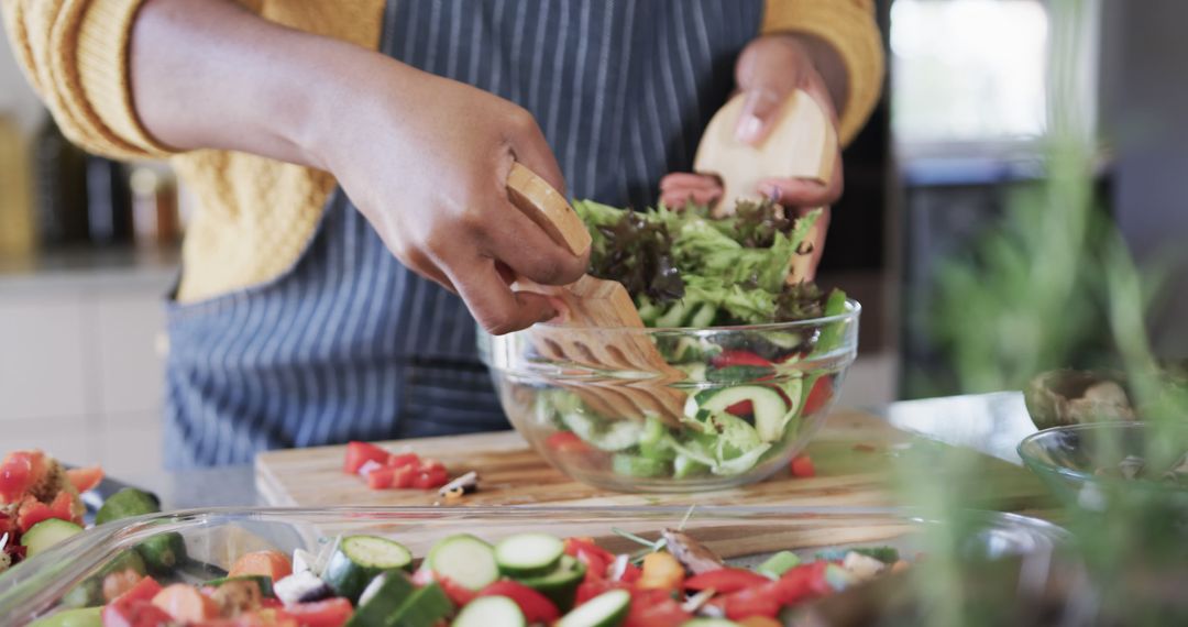 Close-Up of a Person Tossing Fresh Vegetable Salad in Kitchen - Free Images, Stock Photos and Pictures on Pikwizard.com