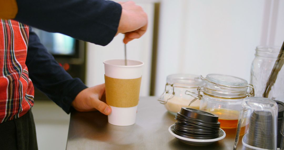 Person Stirring Coffee in Takeaway Cup at Cafe Counter - Free Images, Stock Photos and Pictures on Pikwizard.com