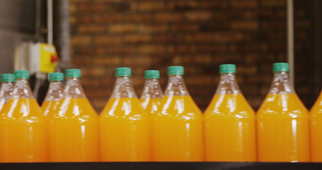 Close up of multiple transparent bottles with orange fluid in bottle factory - Free Images, Stock Photos and Pictures on Pikwizard.com