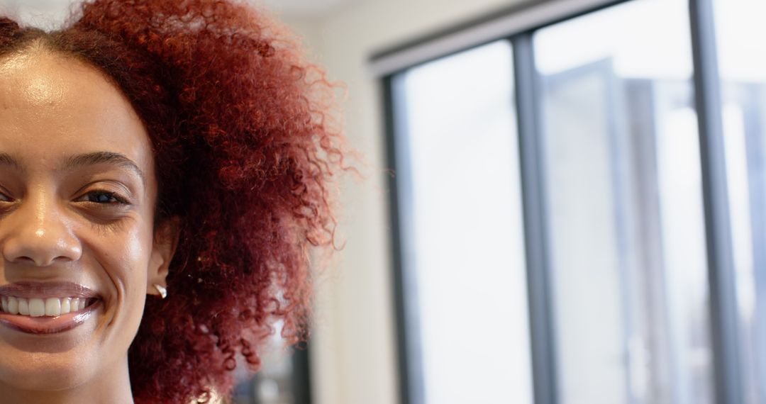 Smiling Woman with Curly Hair Near Window Blinds