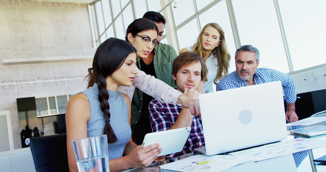 Diverse Team Analyzing Project on Laptop in Modern Office