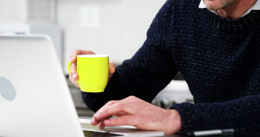 Man Working from Home Using Laptop in Modern Kitchen