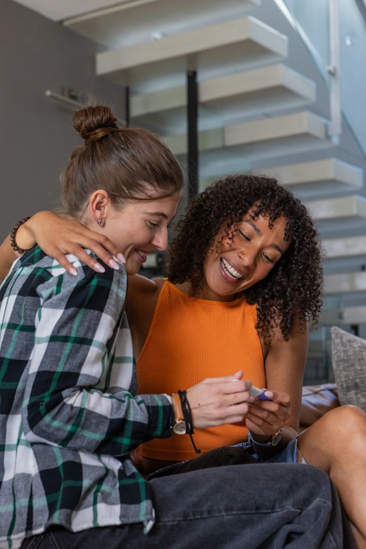 Diverse Friends Sharing Excitement Over Device in Modern Living Space