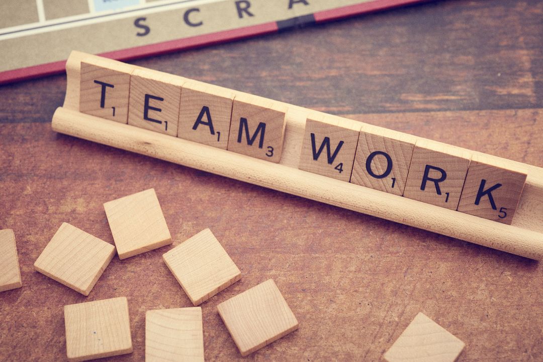 Scrabble Tiles Forming the Word Teamwork on Wooden Board