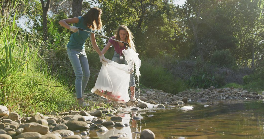 Two Young Women Collecting Trash Along Stream in Nature Cleanup Effort - Free Images, Stock Photos and Pictures on Pikwizard.com