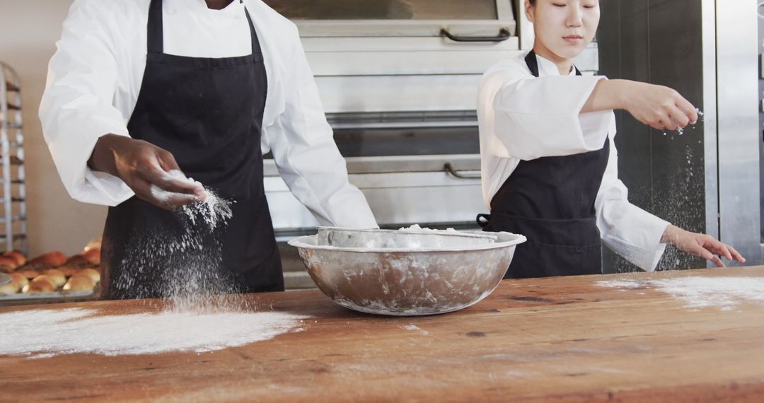 Professional Bakers Sprinkling Flour on Wooden Table in Commercial Kitchen - Free Images, Stock Photos and Pictures on Pikwizard.com