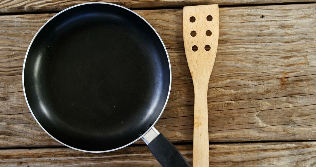 Nonstick Frying Pan and Wooden Spatula on Rustic Wooden Surface - Free Images, Stock Photos and Pictures on Pikwizard.com