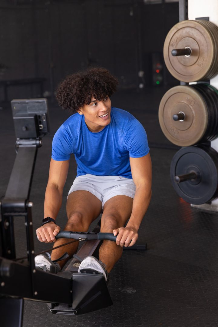 Energetic Man Exercising on Rowing Machine in Gym Environment