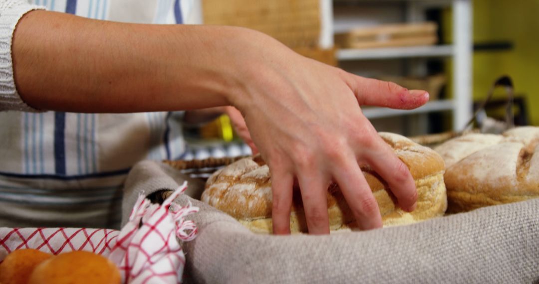 Hand Selecting Freshly Baked Artisan Bread in Bakery - Free Images, Stock Photos and Pictures on Pikwizard.com