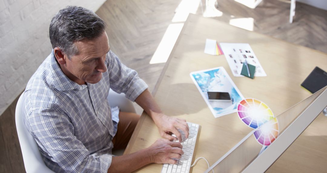 Man Working on Graphic Design Project at Desk in Bright Office - Free Images, Stock Photos and Pictures on Pikwizard.com