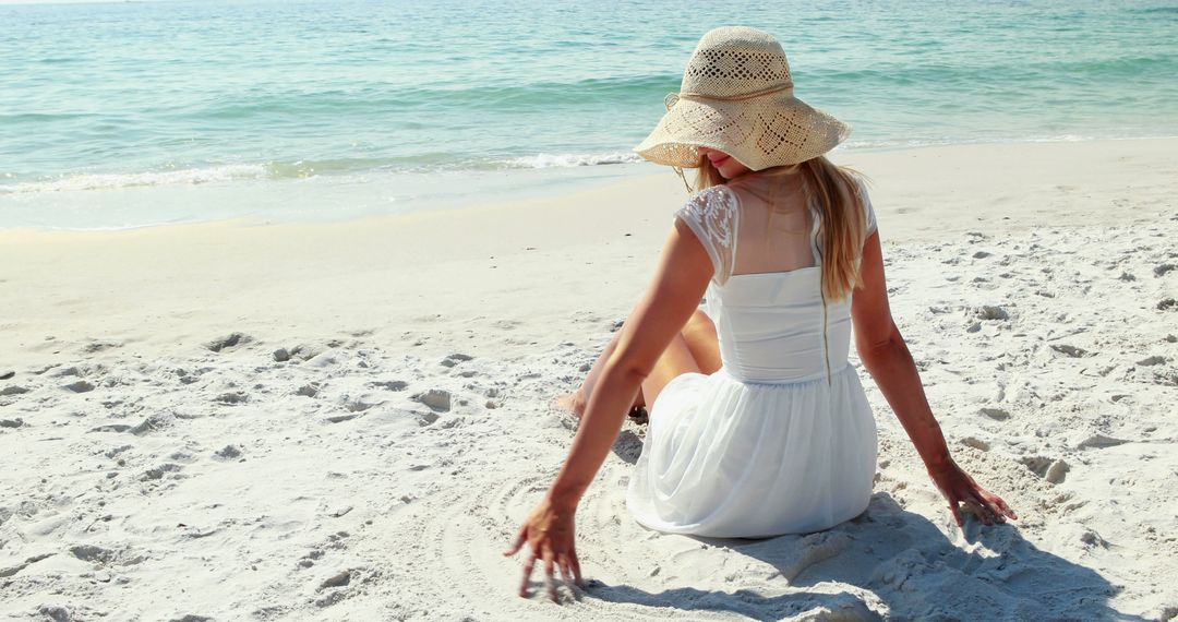 Woman in White Dress and Straw Hat Sitting on Sandy Beach - Free Images, Stock Photos and Pictures on Pikwizard.com