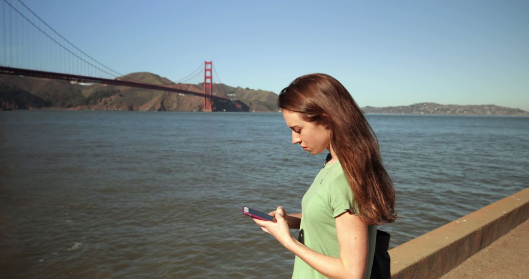 Young Woman Using Phone Near Golden Gate Bridge - Free Images, Stock Photos and Pictures on Pikwizard.com