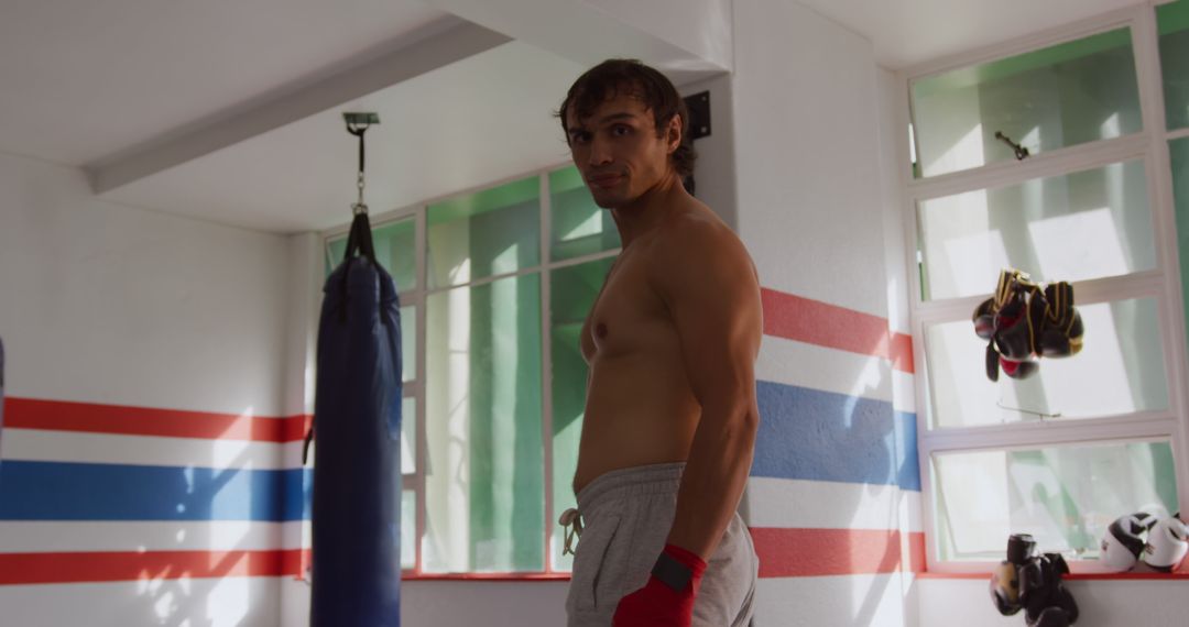 Confident Male Boxer Posing in Gym with Boxing Equipment - Free Images, Stock Photos and Pictures on Pikwizard.com