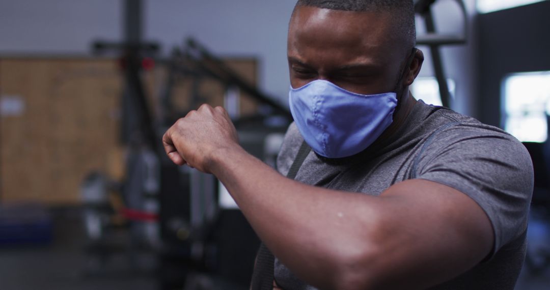 Man Sneezing into Elbow in Gym Wearing Protective Mask - Free Images, Stock Photos and Pictures on Pikwizard.com