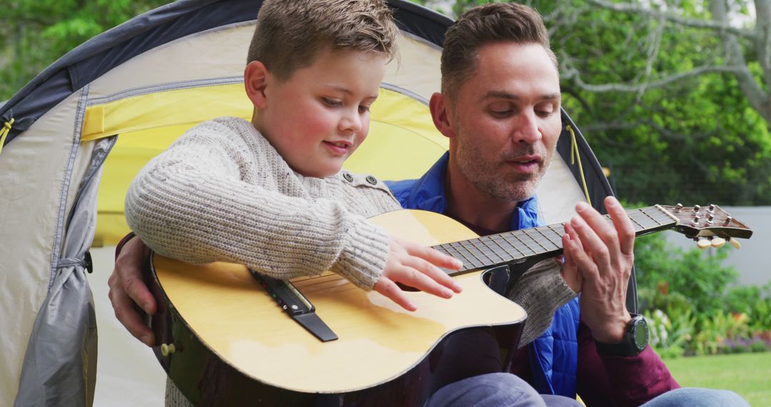 Father Teaching Son to Play Guitar During Outdoor Camping - Free Images, Stock Photos and Pictures on Pikwizard.com