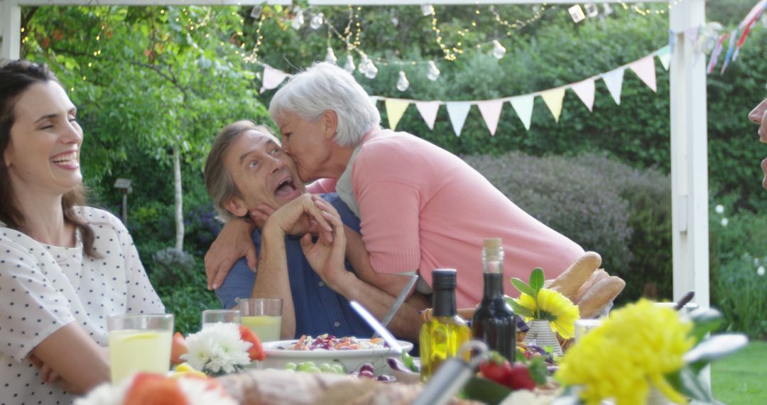 Senior Woman Kissing Man's Cheek at Family Outdoor Gathering - Free Images, Stock Photos and Pictures on Pikwizard.com