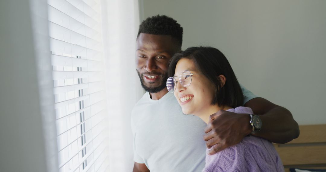 Happy Multiracial Couple Embracing by Window - Free Images, Stock Photos and Pictures on Pikwizard.com