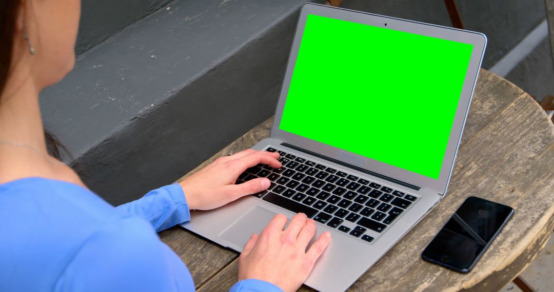 Woman Using Laptop with Green Screen by Smartphone on Table - Free Images, Stock Photos and Pictures on Pikwizard.com