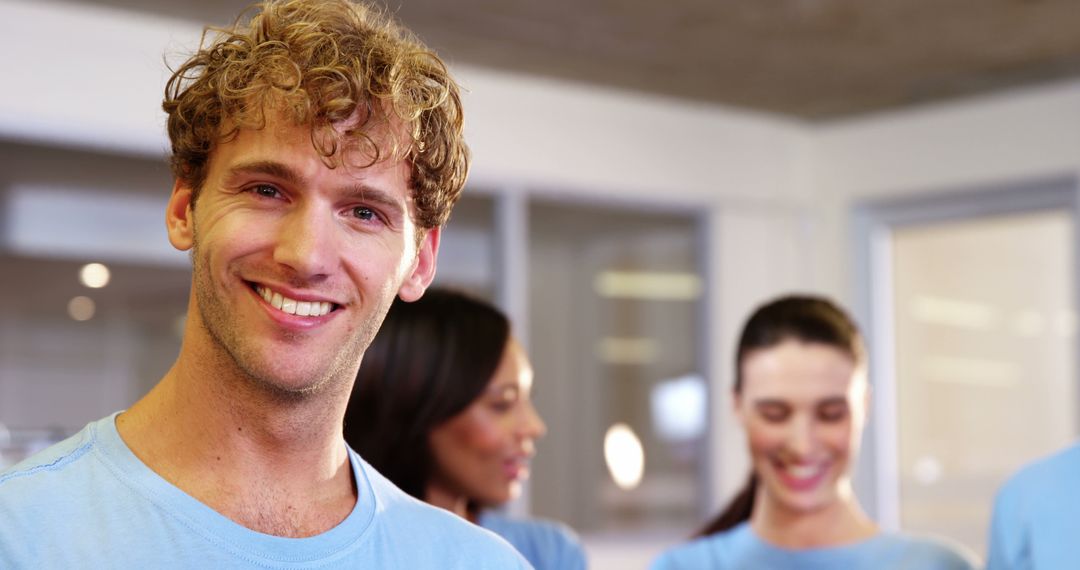 Smiling Man in Casual Office with Colleagues in Background - Free Images, Stock Photos and Pictures on Pikwizard.com