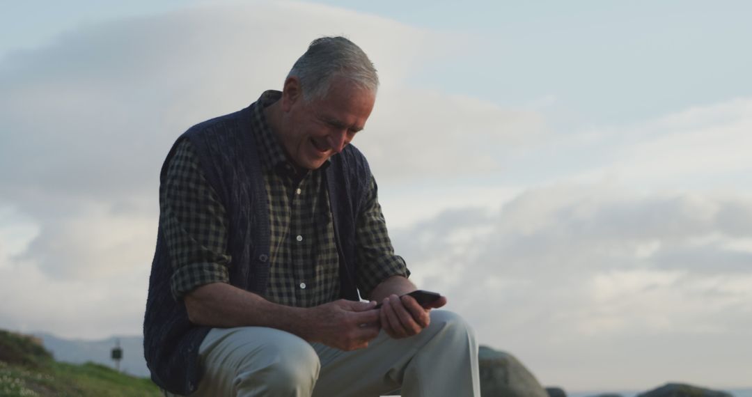 Senior man enjoying smartphone outdoors at seaside during sunset - Free Images, Stock Photos and Pictures on Pikwizard.com