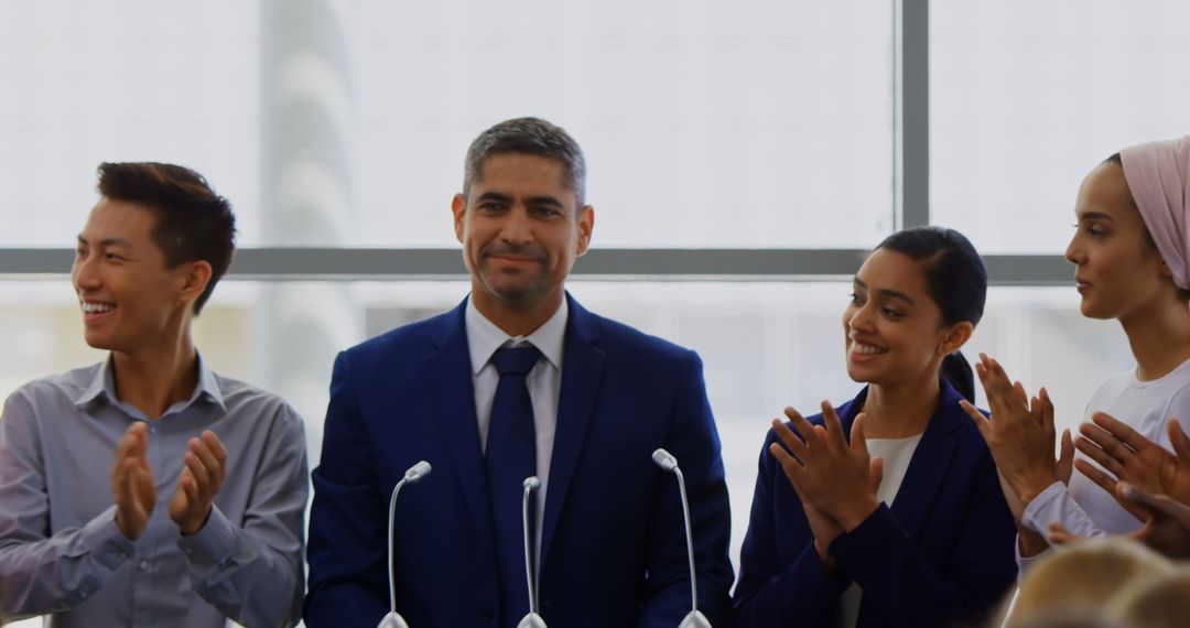 Confident Businessman Standing at Podium with Supportive Team Applauding
