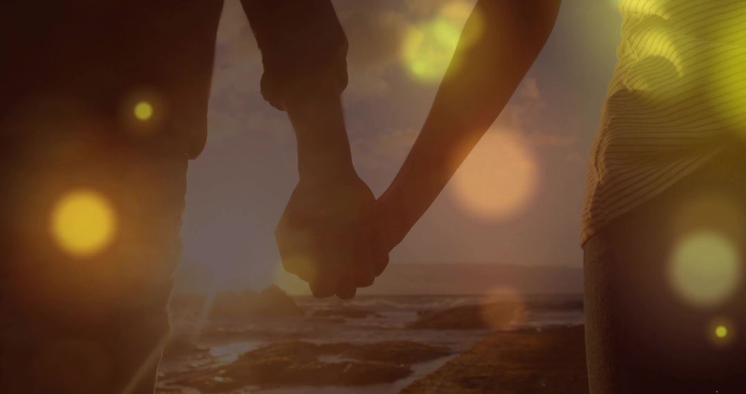 Couple Holding Hands at Sunset on Beach Perspective Shot