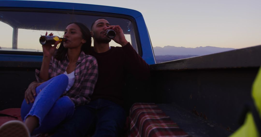 African American couple enjoys drinks in a truck bed at dusk, with copy space - Free Images, Stock Photos and Pictures on Pikwizard.com
