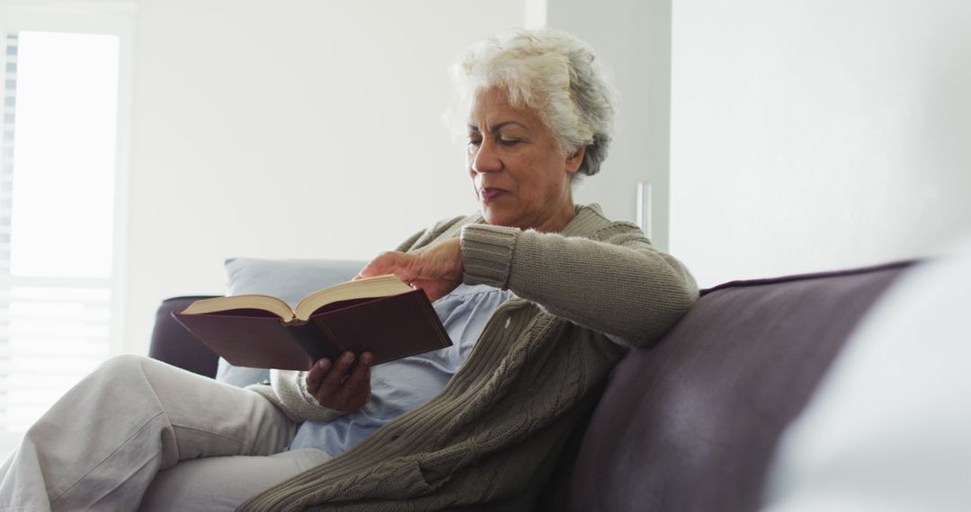 Senior Woman Relaxing on Couch Reading Book - Free Images, Stock Photos and Pictures on Pikwizard.com