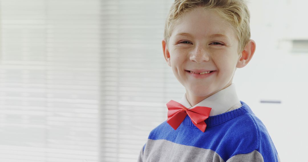 A cheerful boy in a red bow tie and blue sweater hints at a formal event. - Free Images, Stock Photos and Pictures on Pikwizard.com