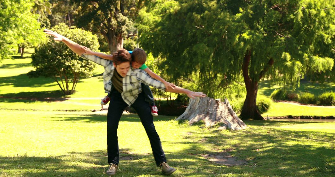 Father and Son Playing Airplane in Sunny Park - Free Images, Stock Photos and Pictures on Pikwizard.com