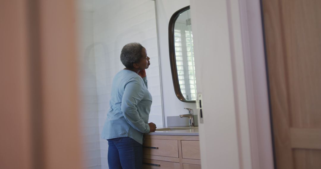 Senior Woman Looking in Bathroom Mirror Contemplative Moment - Free Images, Stock Photos and Pictures on Pikwizard.com