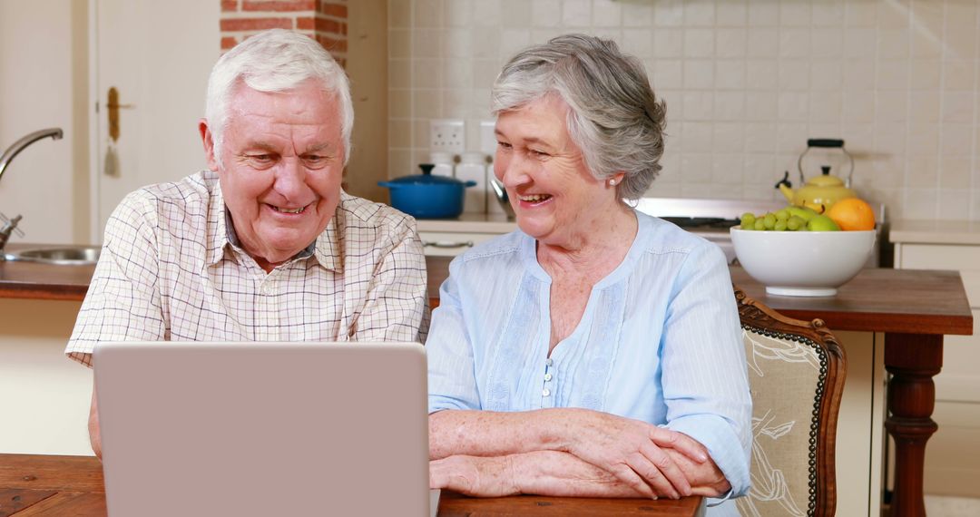 Smiling Senior Couple Using Laptop in Modern Kitchen - Free Images, Stock Photos and Pictures on Pikwizard.com