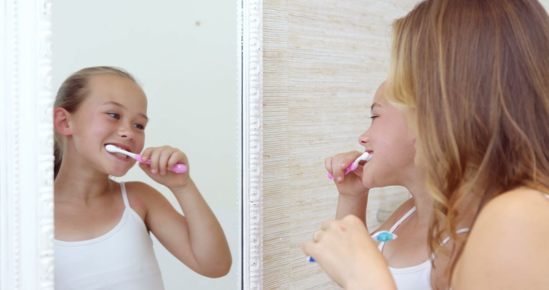 Young Girls Brushing Teeth Together in Bathroom Mirror - Free Images, Stock Photos and Pictures on Pikwizard.com