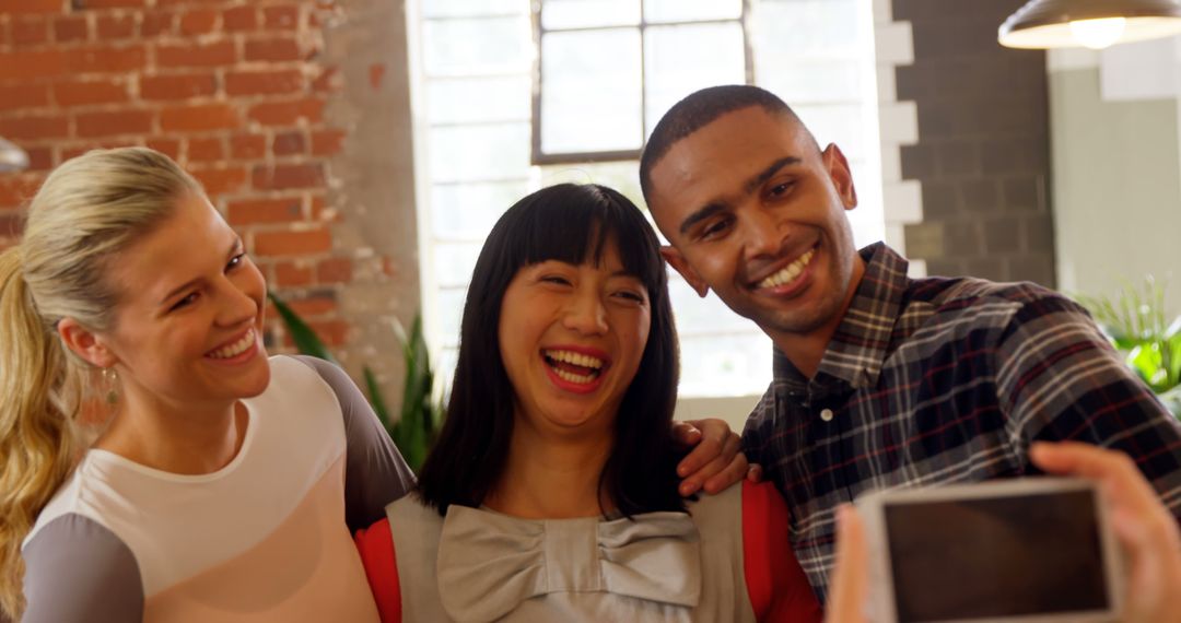 Diverse Friends Smiling While Taking a Group Selfie in a Bright Studio