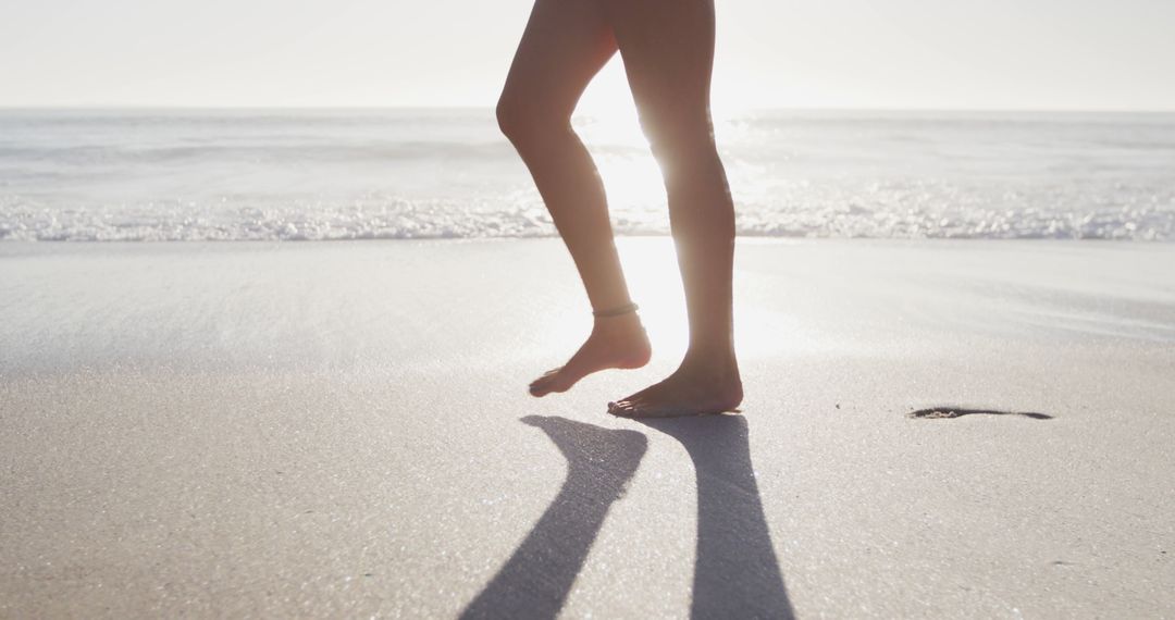 Person Walking on Sunny Beach with Calm Waves - Free Images, Stock Photos and Pictures on Pikwizard.com