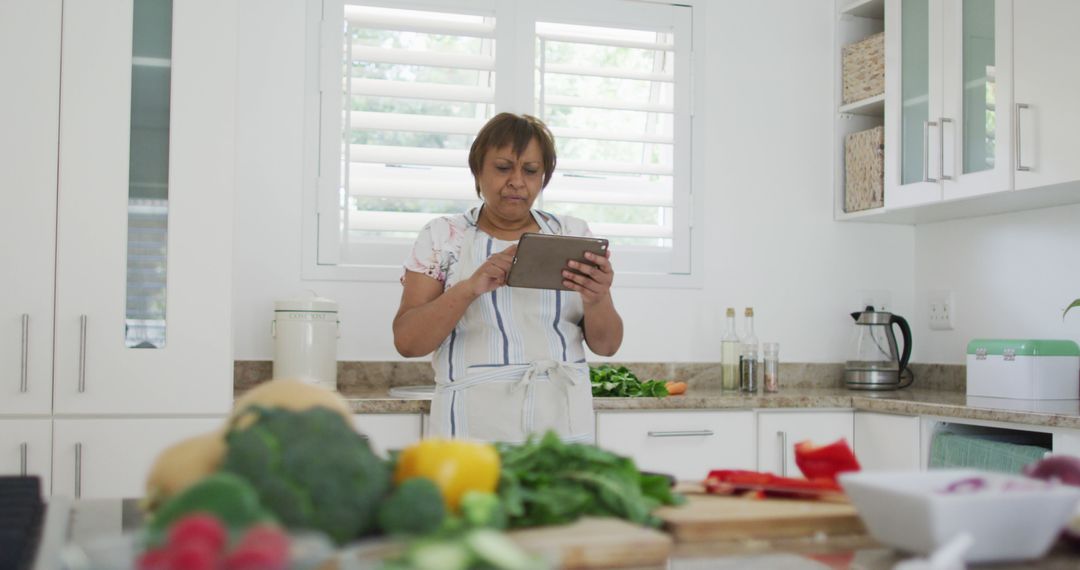 Senior Woman Using Tablet to View Recipe in Kitchen - Free Images, Stock Photos and Pictures on Pikwizard.com