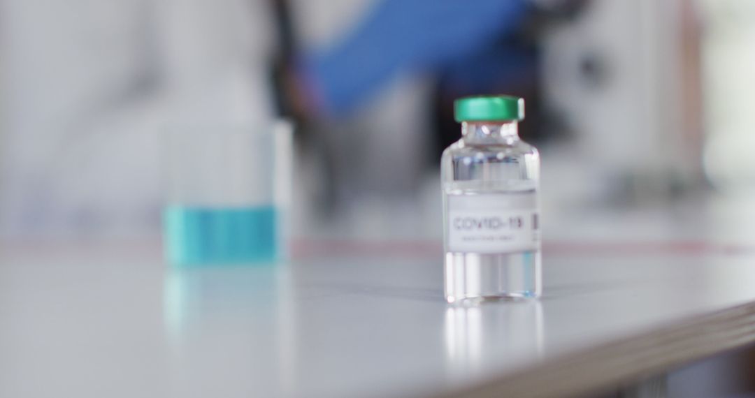 COVID-19 Vaccine Vial on Laboratory Table with Blue Liquid in Background - Free Images, Stock Photos and Pictures on Pikwizard.com