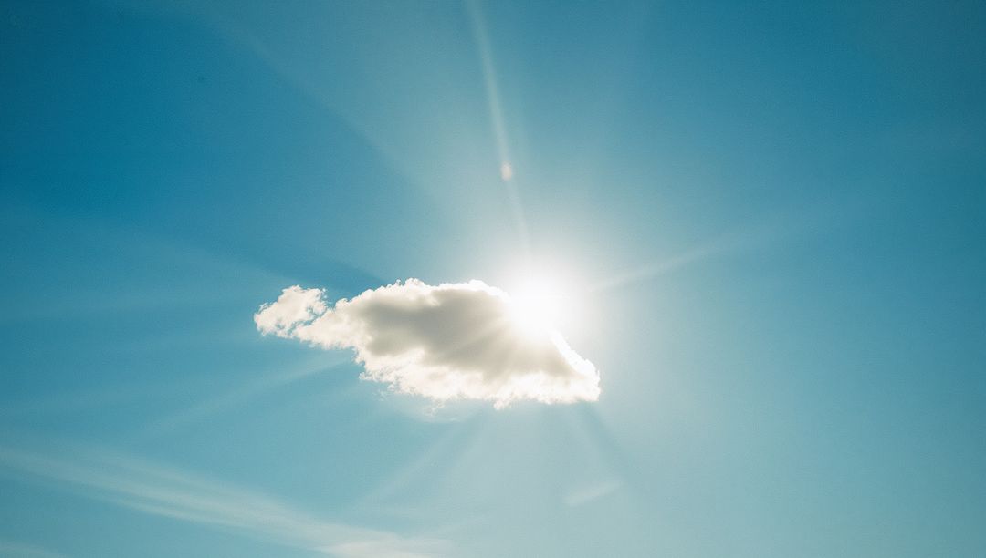 Serene Cloud Obscuring Sun in Clear Blue Sky with Radiating Sunbeams
