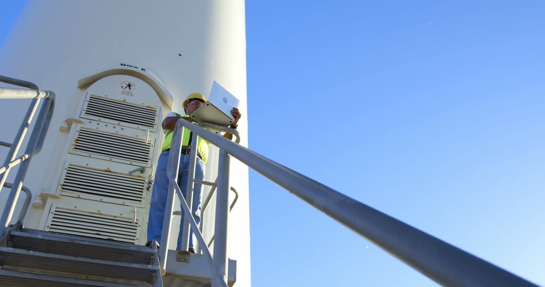 Engineer Inspecting Wind Turbine with Laptop on Bright Day - Free Images, Stock Photos and Pictures on Pikwizard.com