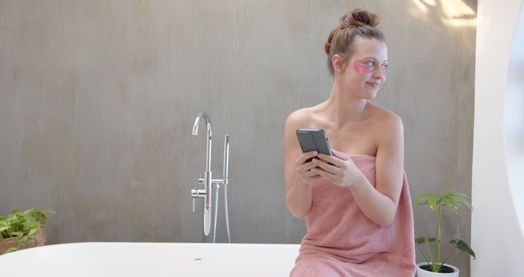 Smiling Woman with Smartphone Relaxing with Skincare in Minimalist Light Bathroom