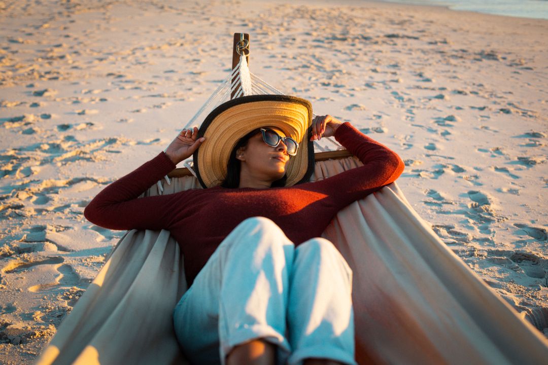 Happy biracial woman relaxing in hammock on beach holding scarf - Free Images, Stock Photos and Pictures on Pikwizard.com