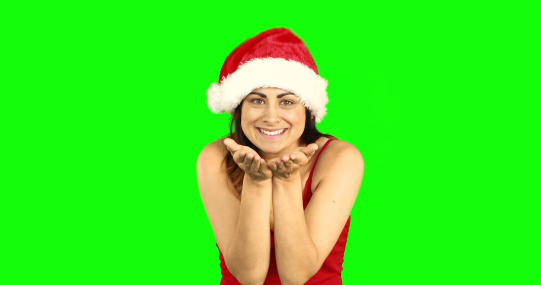 Smiling Woman Wearing Santa Hat Blowing Kiss on Green Background - Free Images, Stock Photos and Pictures on Pikwizard.com