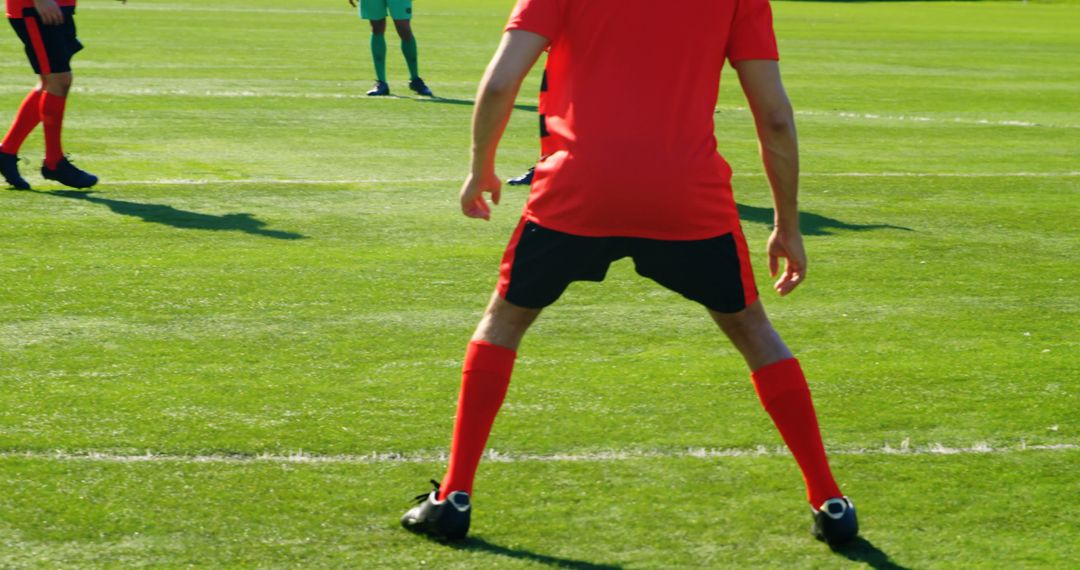 Soccer Player in Red Uniform Ready to Defend on Green Field - Free Images, Stock Photos and Pictures on Pikwizard.com