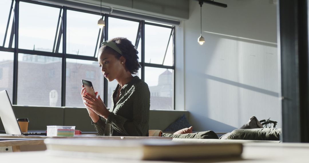 Woman Sitting in Modern Workspace Using Smartphone - Free Images, Stock Photos and Pictures on Pikwizard.com